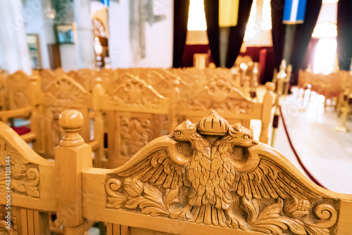 Carved two-headed eagle on a wooden bench in the Interior of majestic St. Demetrios Church. Pilgrimage and worship concept photo