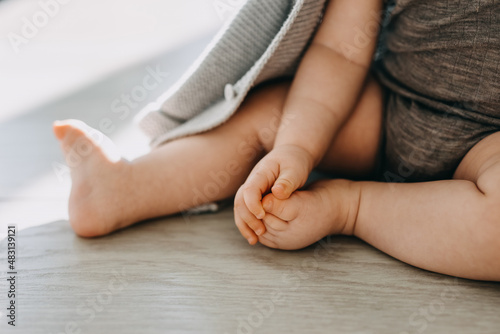Closeup of barefoot feet of a baby sitting on a parquet floor at home. © Bostan Natalia
