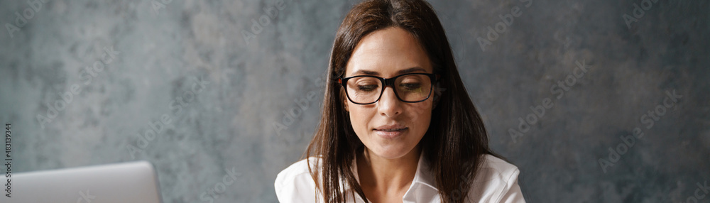 Mid aged brunette businesswoman in shirt sitting Mid aged brunette businesswoman in shirt sitting