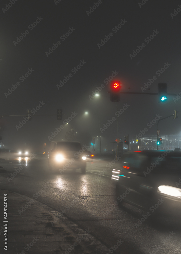 cars driving on city street in foggy night