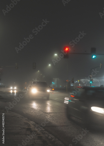 cars driving on city street in foggy night