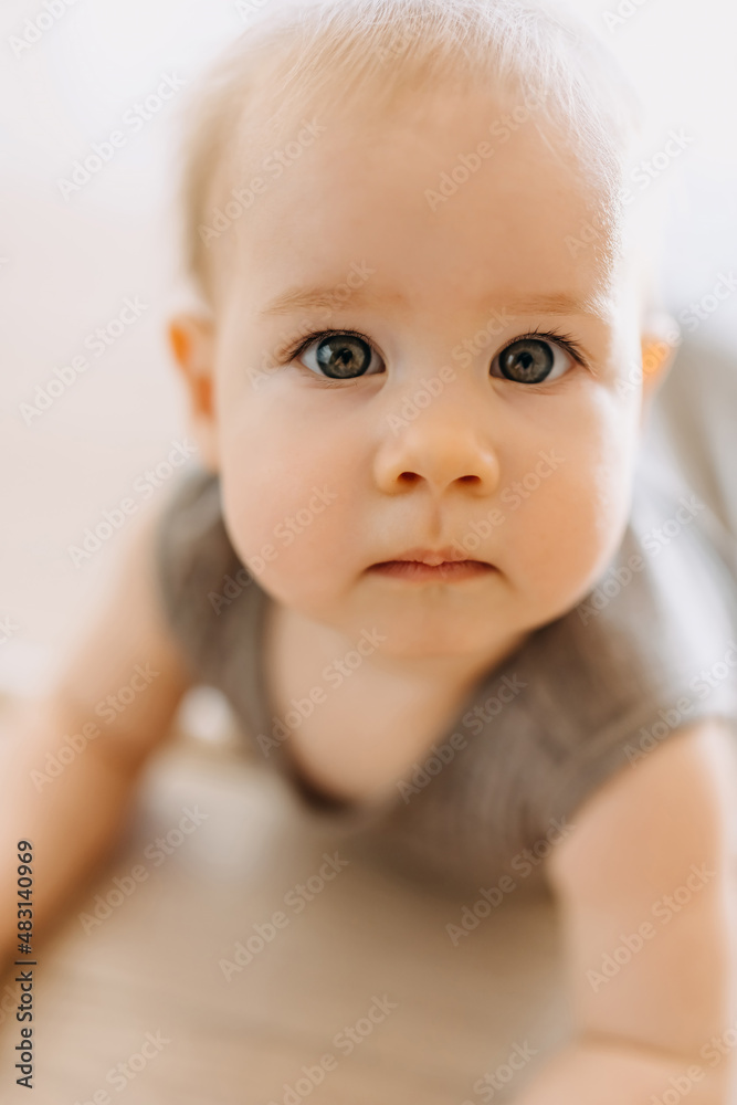 Closeup of a cute serious baby with light grey eyes, looking at camera. Shallow depth of field.