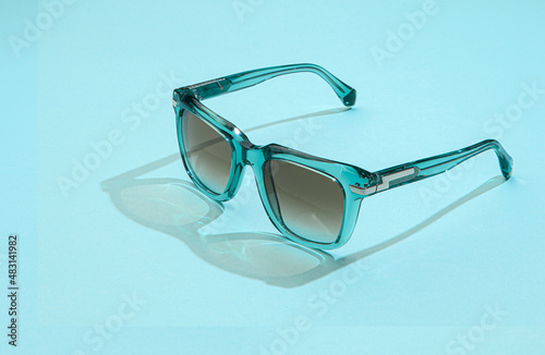 Modern sunglasses on pastel blue background. Sunglasses women with sunlight for summer vacation concept.