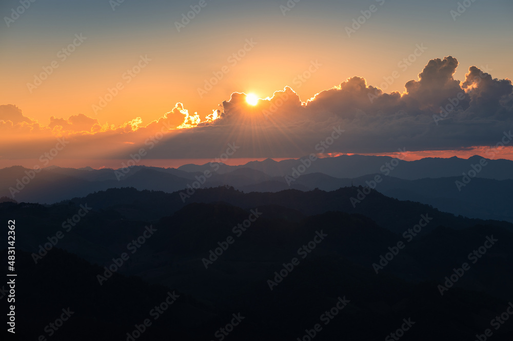 Sunset shining through cloud over mountain range in tropical rainforest at national park