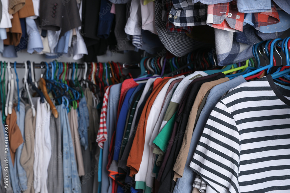 Hangers with stylish clothes on racks as background, closeup. Fast fashion