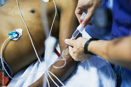 Drug administration via an iv drip. Cropped shot of a doctor inserting an iv drip into a patients arm in an emergency room.