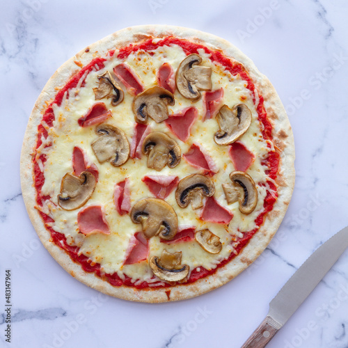 Prosciutto and mushroom pizza on a marble background