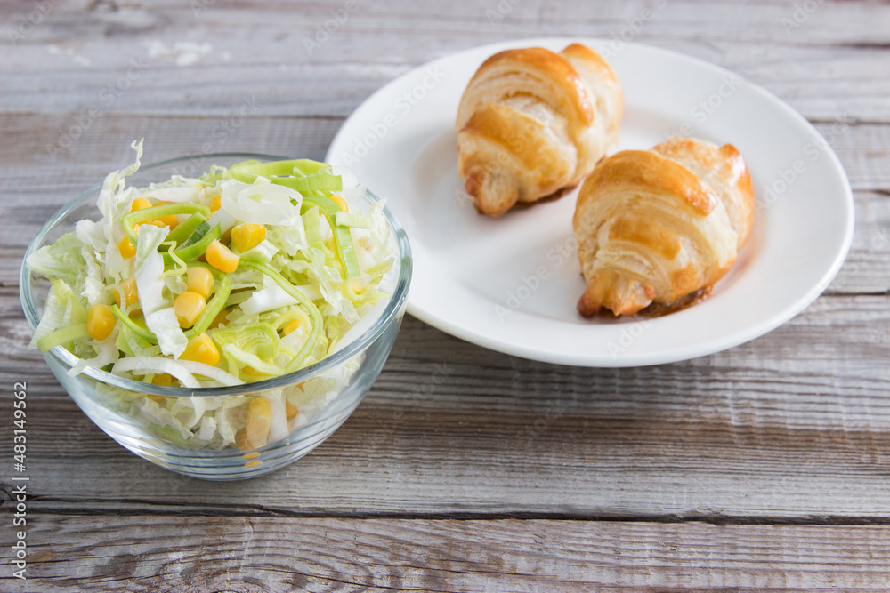 Salad with cheese croissant on wooden background. Salad with cheese croissant on wooden background.
