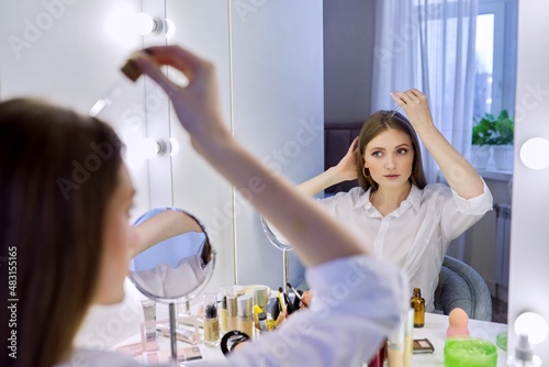 Young woman treating her hair using medical drops.