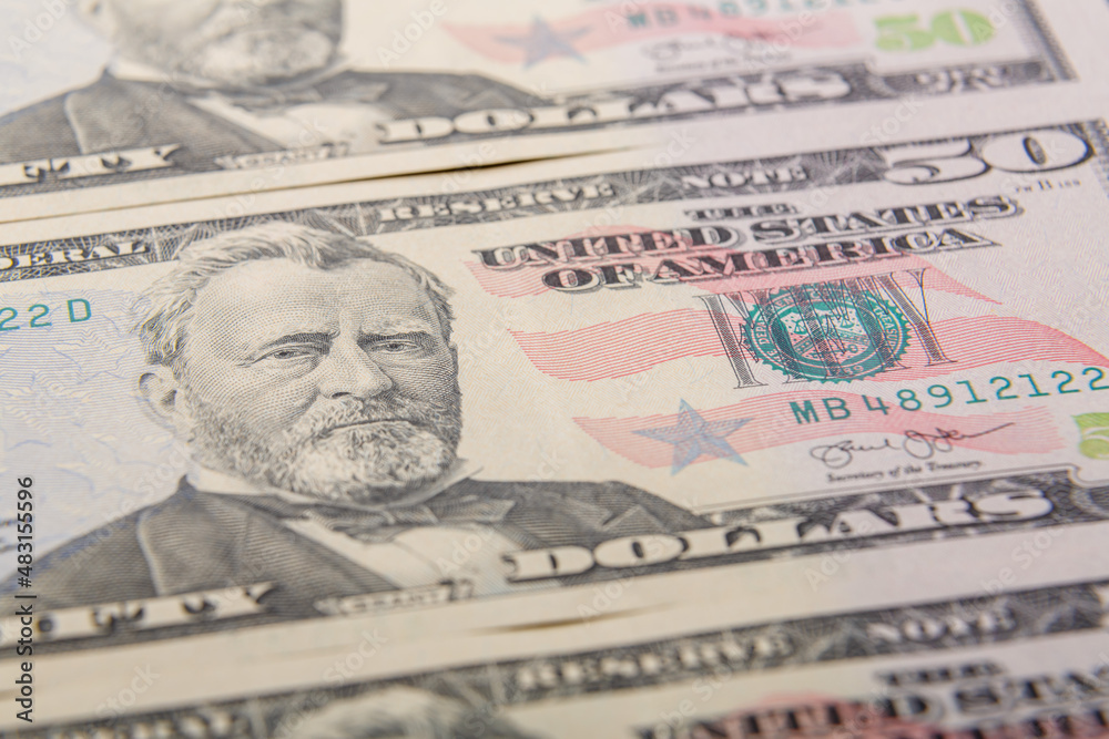 Fragments of fifty dollar bills on a flat surface, very close-up.