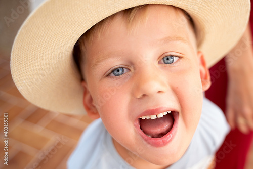 Happy child boy with big beautiful smile and blue eyes wearing summer hat.