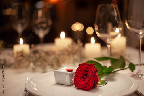 romantische Atmosphäre beim candlelight-dinner mit roter Rose und kleinem Geschenk photo