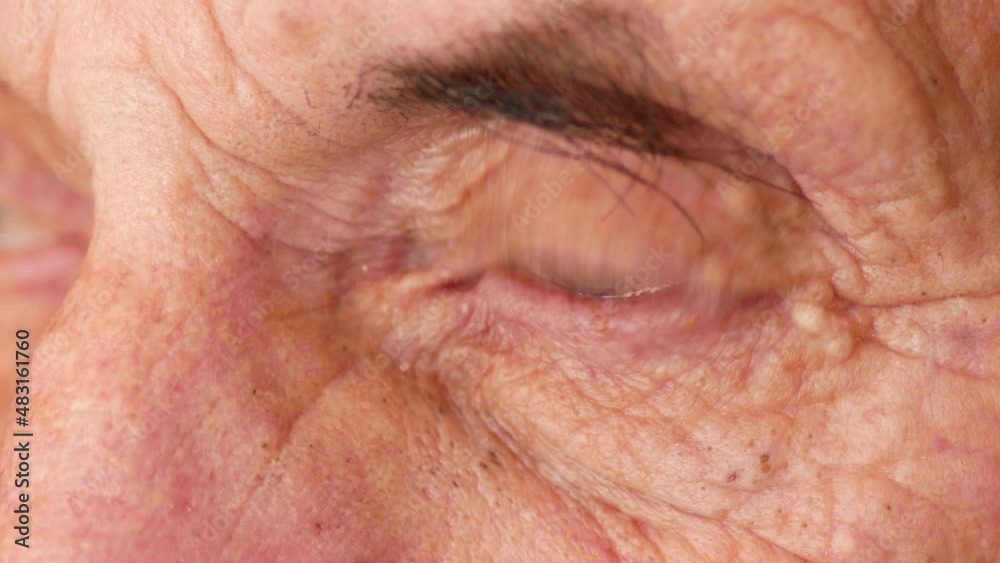 Thoughtful and sad wrinkled eyes of a Caucasian elderly man over 70 looking into the distance. Aging and venerable age. Nursing home theme. Macro details of the face of a pensioner. Selective focus