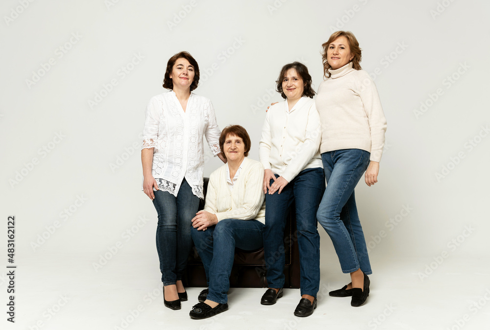 a cute grandmother sits on an armchair with her daughters and has fun on a white background.grandmother with her daughters. pensioner with women on white background a cute grandmother sits on an armchair with her daughters and has fun on a white background.grandmother with her daughters. pensioner with women on white background