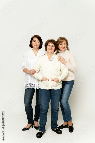 beautiful grandmother smiles being on a white background with her daughters. group of happy women. grandmother hugs her daughter. family day