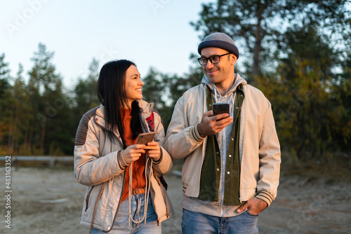 Waist up portrait view of the caucasian couple in love looking at each other while enjoying of the vacation with forest at the background