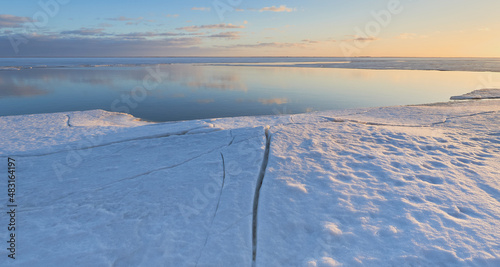 Coast of Gulf of Finland of the Baltic Sea in the end of winter: open water, before sunset, ice cracks.