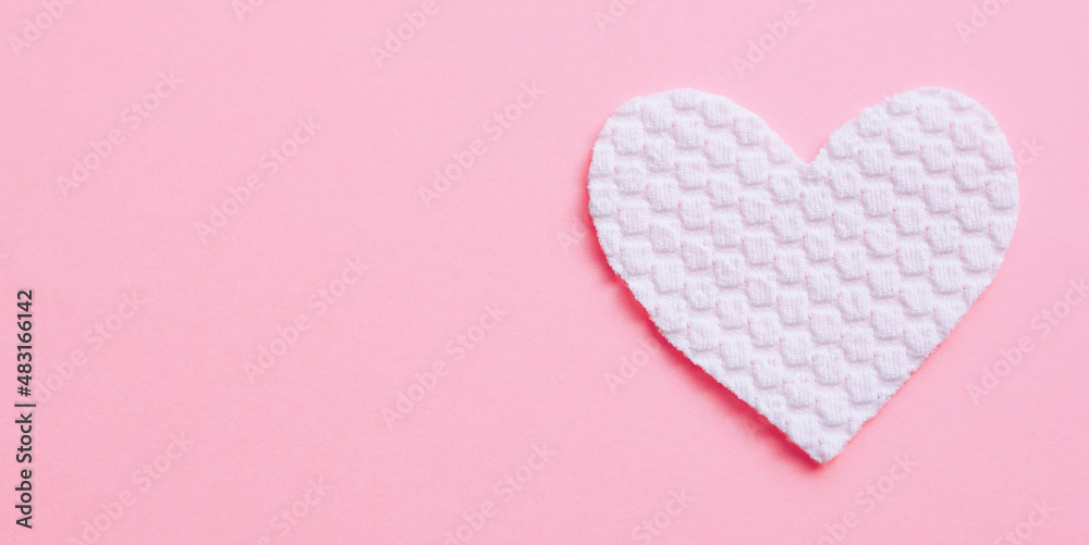 White fabric heart on pale pink table