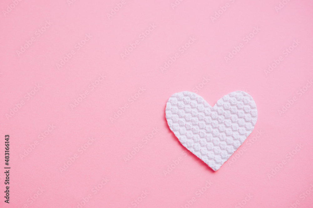 White fabric heart on pastel pale pink table. White fabric heart on pastel pale pink table.
