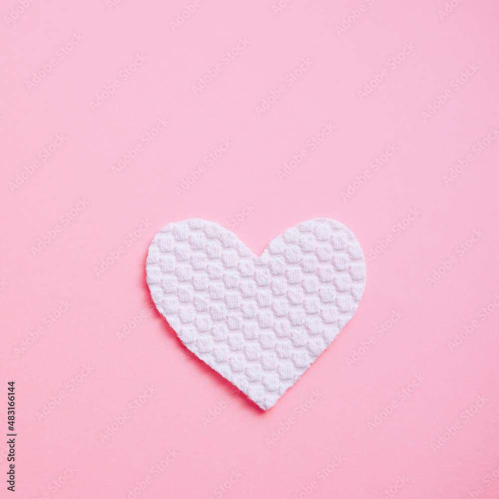 White fabric heart on pale pink table