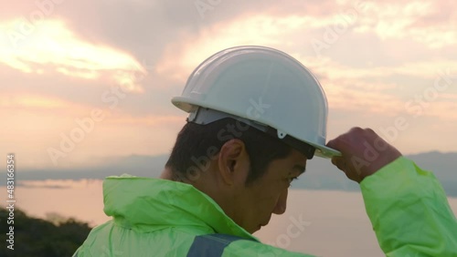 a man engineer is putting a protective helmet on her head at sunset..