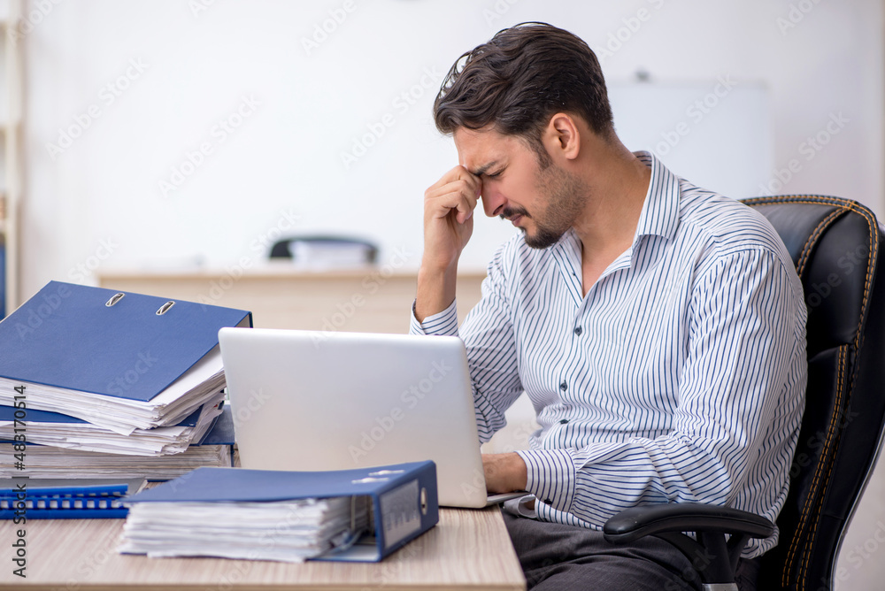 Young male employee and too much work in the office Young male employee and too much work in the office