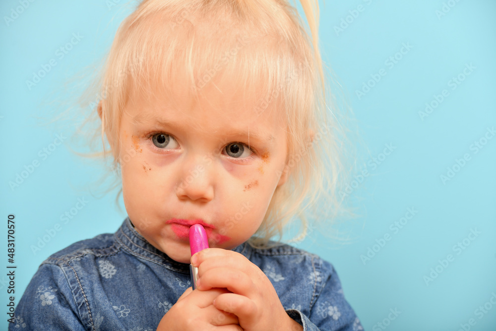 A little girl with a parental lipstick brings beauty to her face for a glamorous look. A little girl with a parental lipstick brings beauty to her face for a glamorous look.