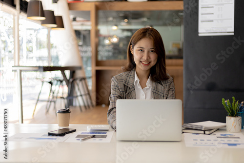 A businesswoman is checking company financial documents and using a laptop to talk to the chief financial officer through a messaging program. Concept of company financial management.