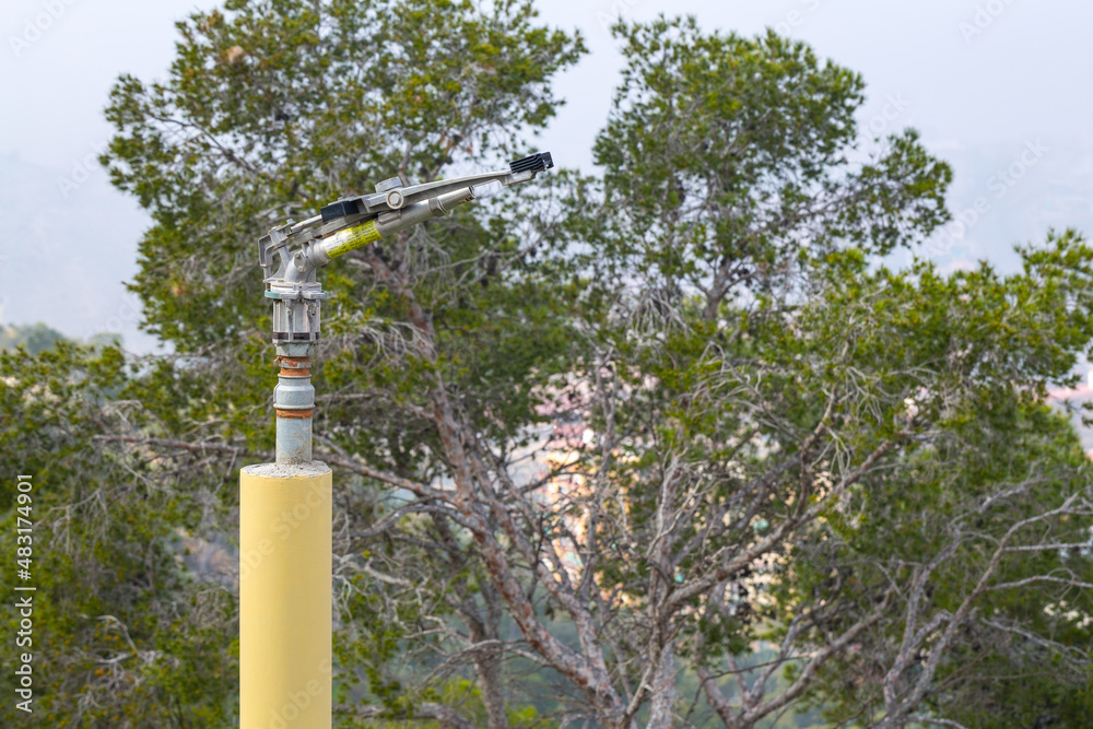 Fototapeta premium Fire sprinkler with a nozzle valve incorporated. An heavy-duty part of the fire protection system of forest or park green flammable plantations in areas with dry and hot climates. Alicante. Spain.