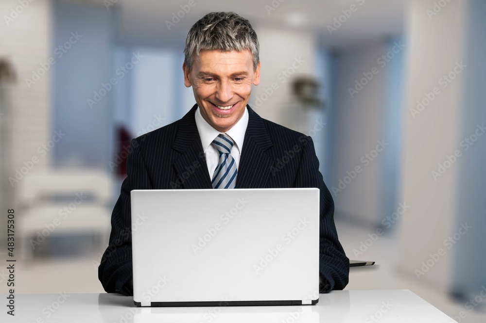 Portrait of happy freelancer man sitting with laptop computer at home office
