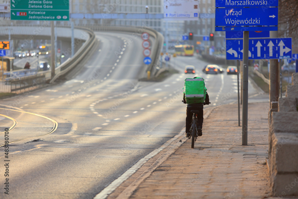 Kurier jedzie na rowerze we Wrocławiu, dostarcza jedzenie.  - obrazy, fototapety, plakaty 
