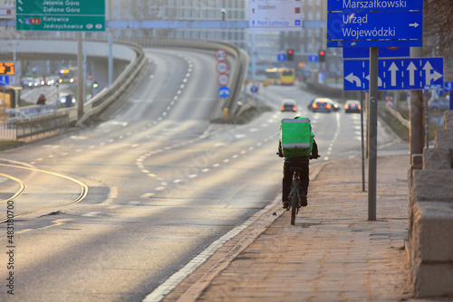 Kurier jedzie na rowerze we Wrocławiu, dostarcza jedzenie. 