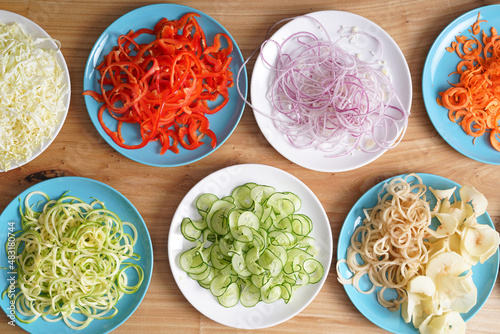 Vegetable spirals from a spiral cutter in plates on a wooden surface. Vegetarian pasta. Home cooking. Top view. photo