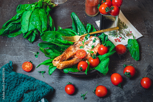 A plate with fresh green raw spinach and fried wild salmon, tomatoes and cream cheese sauce 