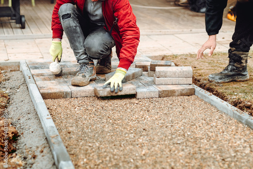 Industrial construction worker laying pavement stones