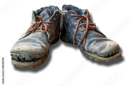 Isolated pair of dirty boots. Old worn dark blue leather shoes with variegated brown laces on white background. The concept of poverty, homelessness, lack of money. Selective focus.