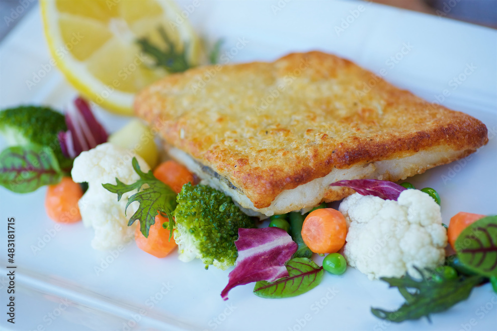 Pollock fish, telapia or hake in breaded with vegetables. The concept of a menu for a restaurant or cafe. Pollock fish, telapia or hake in breaded with vegetables. The concept of a menu for a restaurant or cafe.