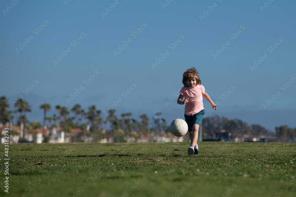 Boy child playing football on football field. Kid playing soccer. Kids training soccer.