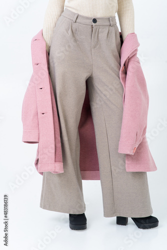 Billede på lærred The woman takes off her pink coat, wearing beige warm turtleneck, gray wide trousers and black heeled shoes