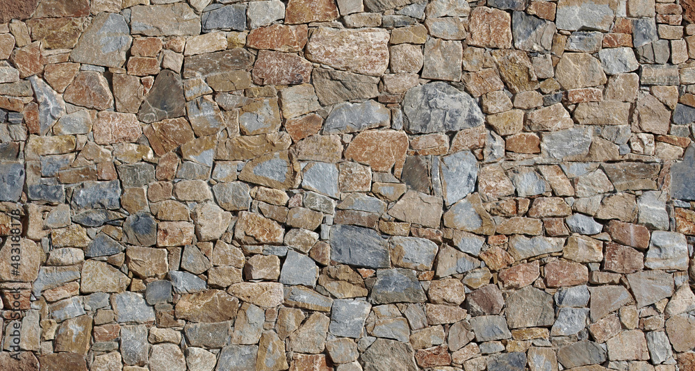 Fototapeta premium Rustic exterior wall made from brown flat natural stones of different sizes arranged randomly. Background and texture