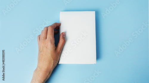 A mockup of an close book in womans hand isolated on blue .mockup with shadow. book endpaper. Blank catalog, magazines or brochure.