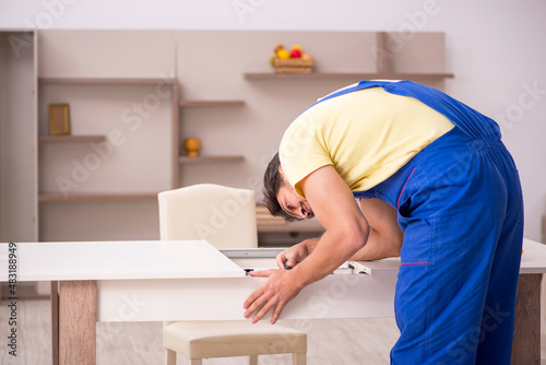 Young male carpenter repairing table at home