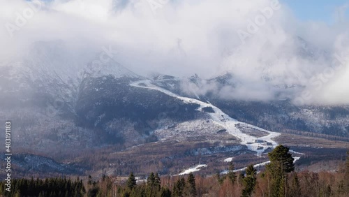 Timelapse of clouds over landscape under High Tatras rocky mountains in spring season, Slovakia. Green meadows in contrast with mountains covered with snow.