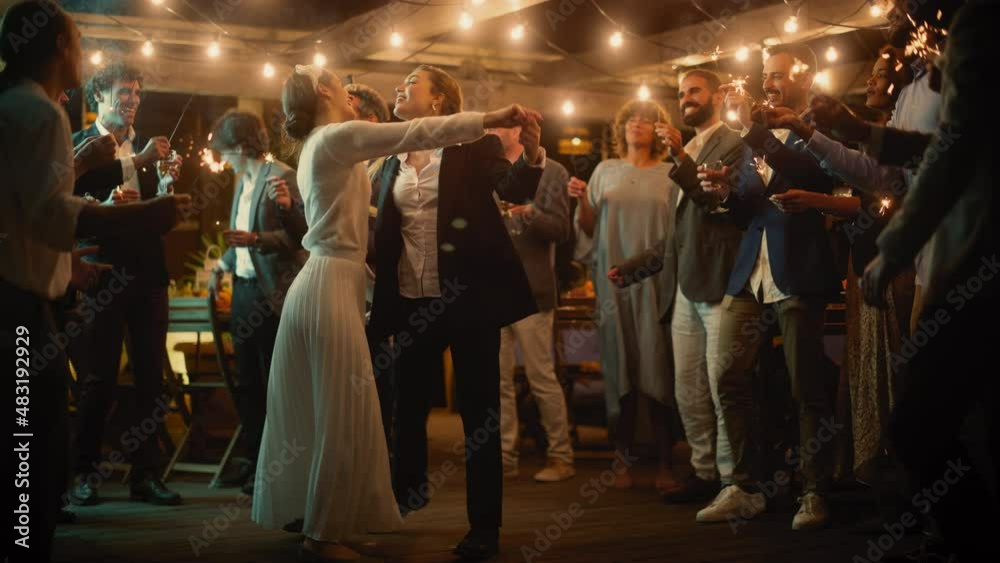 Beautiful Happy Lesbian Couple Celebrate Wedding at an Evening Reception Party with Diverse Multiethnic Friends. Queer Newlyweds Dancing at a Restaurant Venue. LGBTQ Relationship and Family Goals. Beautiful Happy Lesbian Couple Celebrate Wedding at an Evening Reception Party with Diverse Multiethnic Friends. Queer Newlyweds Dancing at a Restaurant Venue. LGBTQ Relationship and Family Goals.
