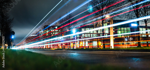 Long exposure photo of a bus passing on a street at night.