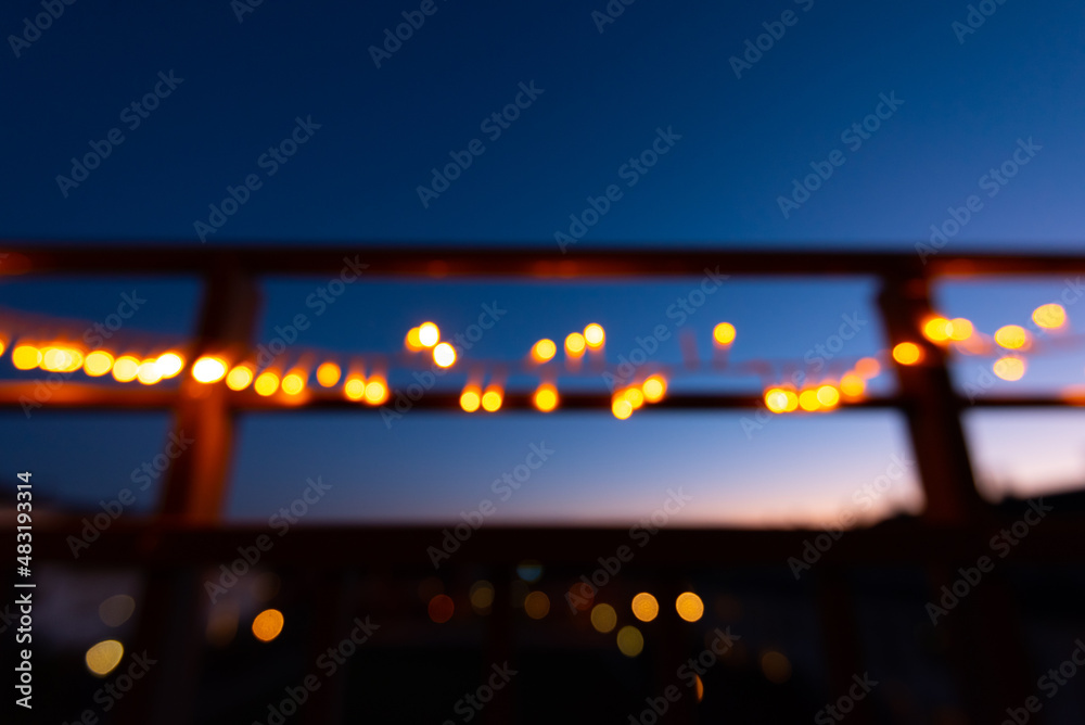 Out of focus christmas lights on the railings of a balcony at night.