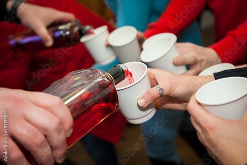 A man pours an alcoholic drink into cups in close-up.