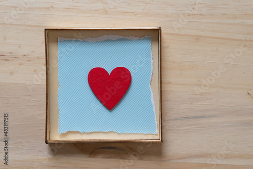 red heart isolated in a box with blue paper and wood