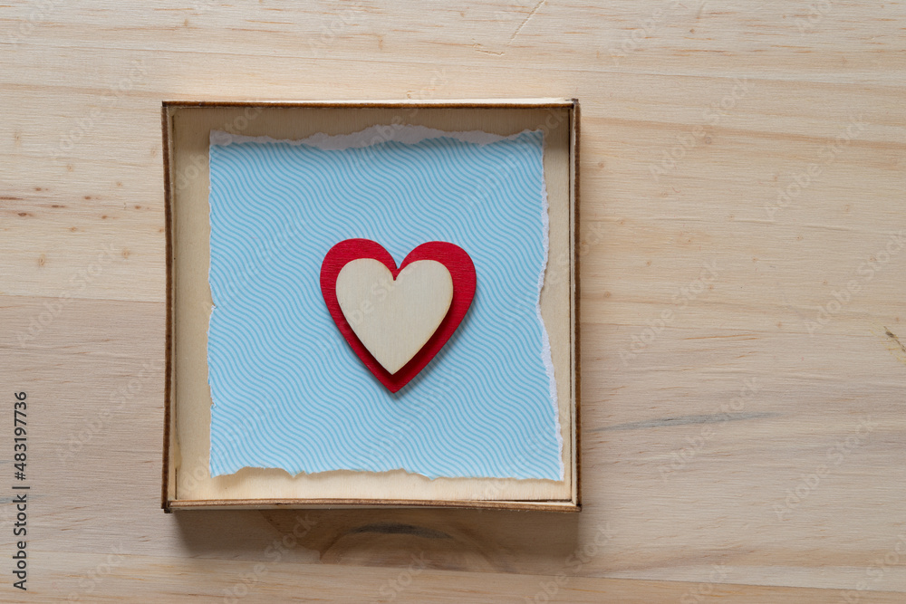 isolated hearts on blue and inside a box on a wooden surface