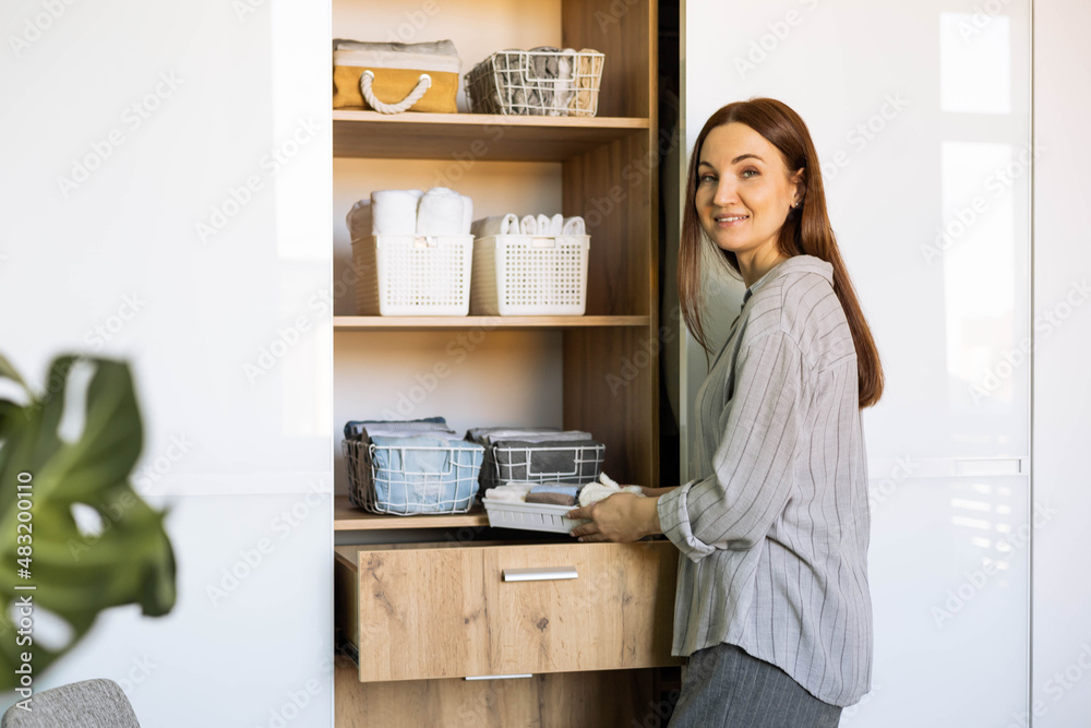 Smiling female putting clothes wardrobe comfortable vertical storage system Marie Kondo method Smiling female putting clothes wardrobe comfortable vertical storage system Marie Kondo method
